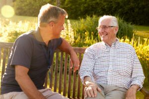Family members sitting with an older adult in a cozy assisted living common area, sharing conversation and smiles.