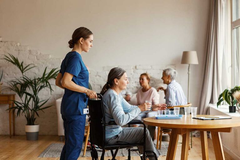 Older resident speaking with a family member in a bright assisted living common room.