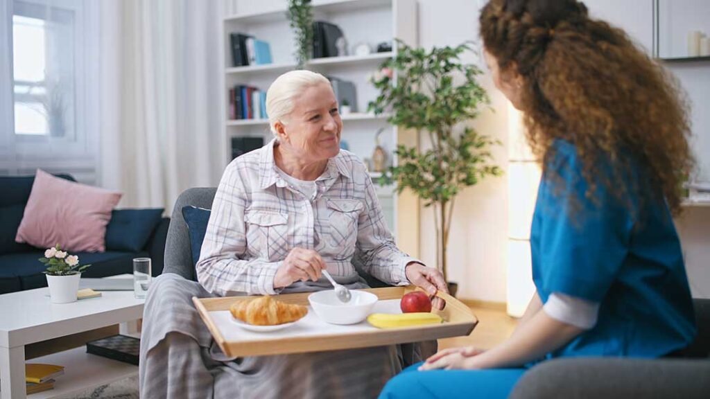 Resident and staff member calmly discussing a concern at a table in an assisted living common room.