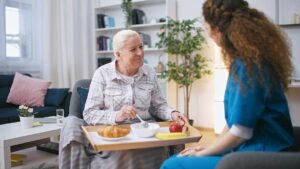 Resident and staff member calmly discussing a concern at a table in an assisted living common room.