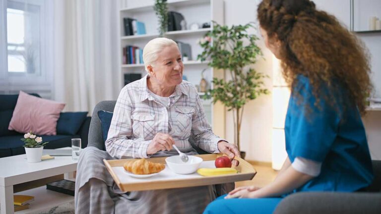 Resident and staff member calmly discussing a concern at a table in an assisted living common room.